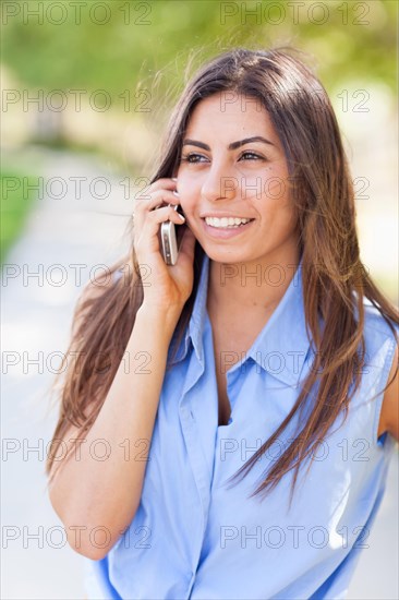 Beautiful young ethnic woman talking on her smartphone outside