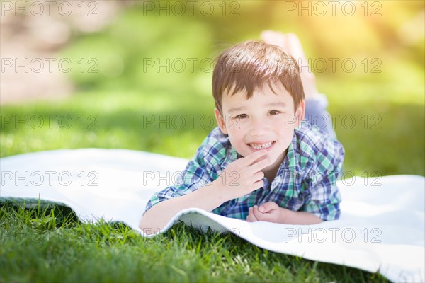 mixed-race chinese and caucasian young boy relaxing outside on the grass
