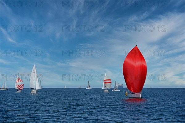 Sailing boat with red sail and sailboats