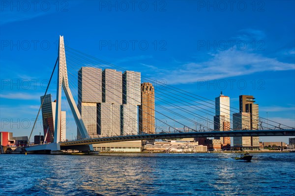 Erasmus bridge over Nieuwe Maas river on sunset with speed boat passing under the bridge. Rotterdam