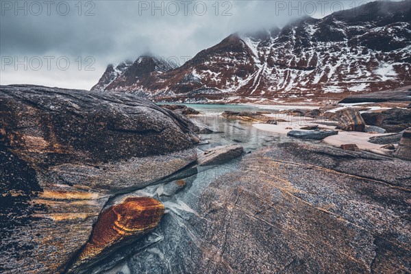 Rocky coast of fjord of Norwegian sea in winter with snow. Haukland beach