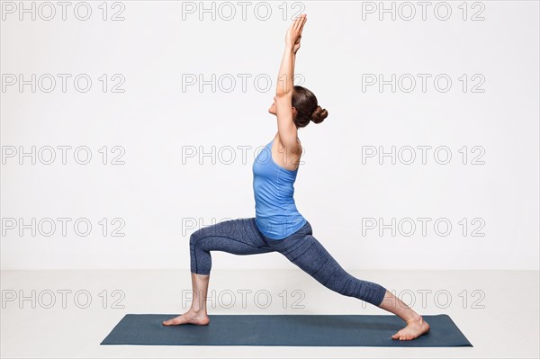 Beautiful sporty fit yogini woman practices yoga asana Virabhadrasana 1