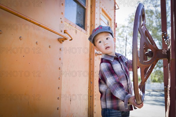 Cute young mixed-race boy having fun outside on railroad car
