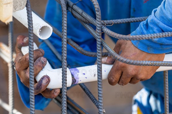 Plumber installing PVC pipe at construction site