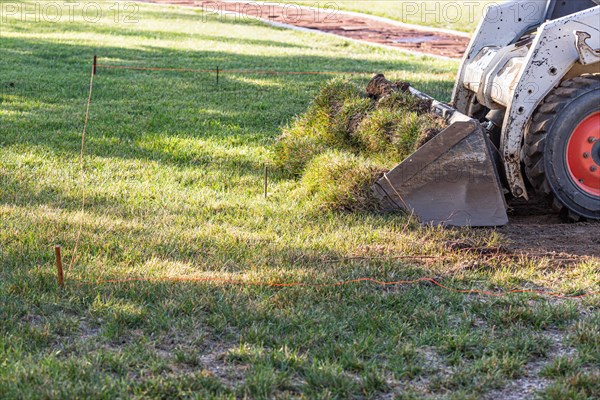 Small bulldozer removing grass from yard preparing for pool installation