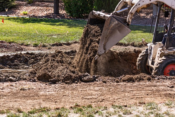 Small bulldozer digging in yard for pool installation