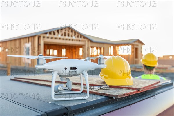 Drone quadcopter next to hard hat helmet at construction site with worker behind