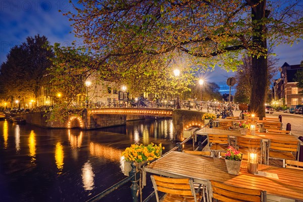 Night view of Amterdam cityscape with cafe tables