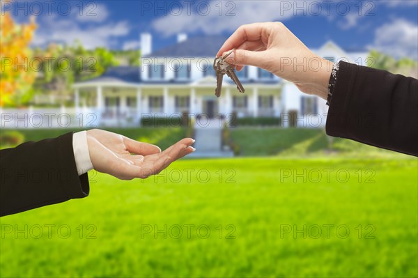 Real estate agent handing over the house keys in front of a beautiful new home