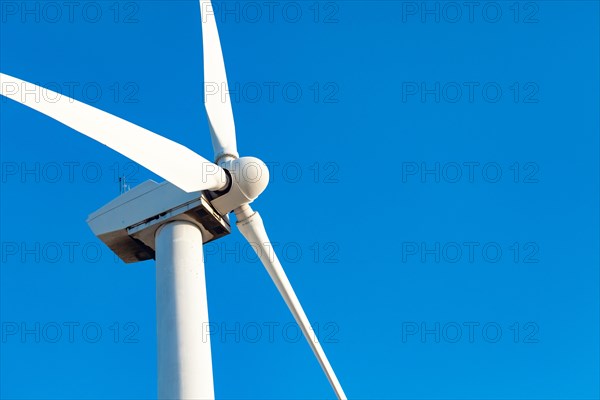 Single wind turbine over dramatic blue sky