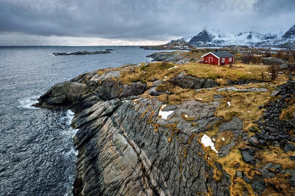 Clif with traditional red rorbu house on Litl-Toppoya islet on Lofoten Islands