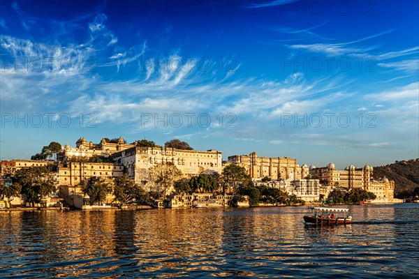 City Palace and tourist boat on lake Pichola on sunset. Udaipur