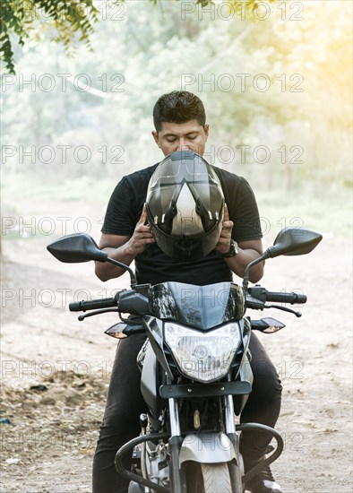 Man on motorcycle putting on helmet