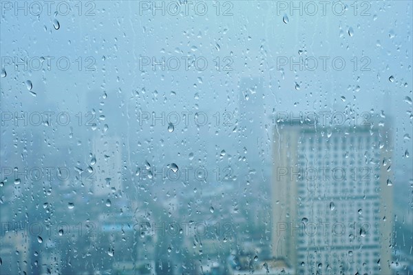 Rain water drops droplets on window glass texture with skyscrapers in background