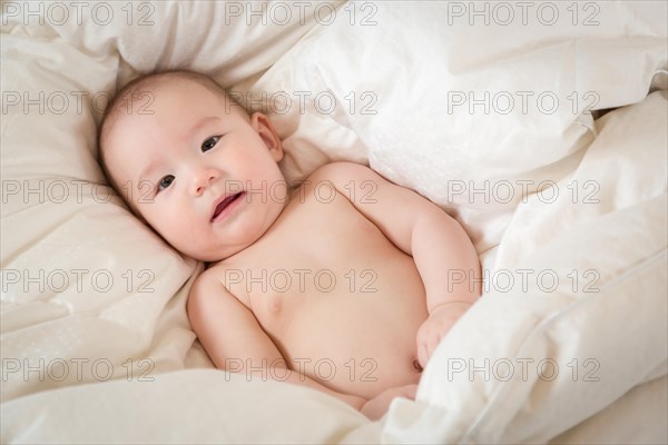 Young mixed-race chinese and caucasian baby boy having fun on his blanket