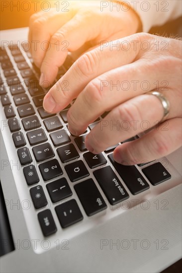 Male hands typing on laptop computer keyboard