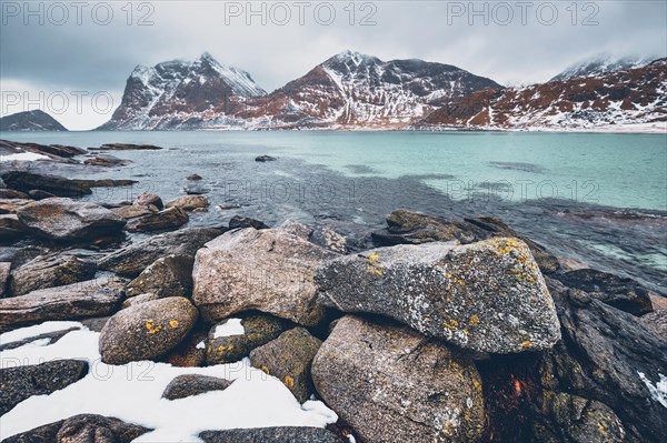 Rocky coast of fjord of Norwegian sea in winter with snow. Haukland beach