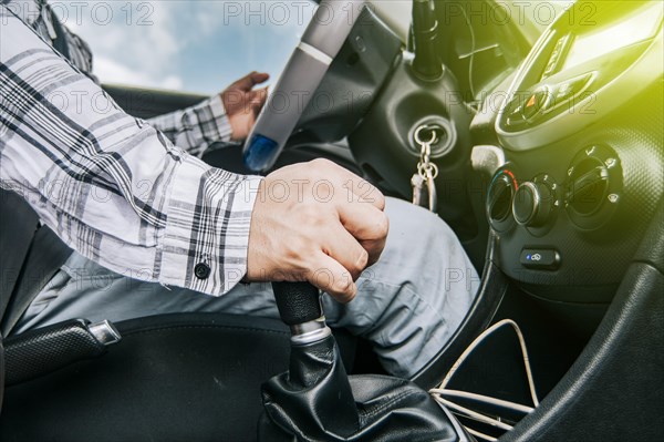Close up of a man's hand on the gear lever of a car
