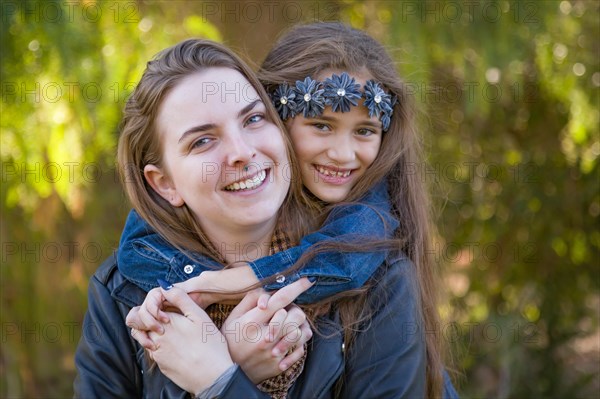 Affectionate caucasian mother and mixed-race daughter portrait outdoors