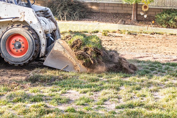 Small bulldozer removing grass from yard preparing for pool installation