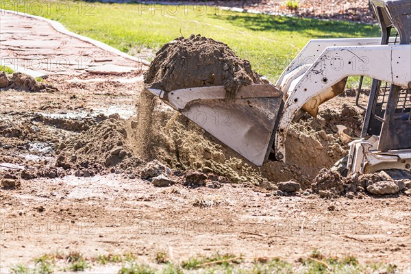 Small bulldozer digging in yard for pool installation