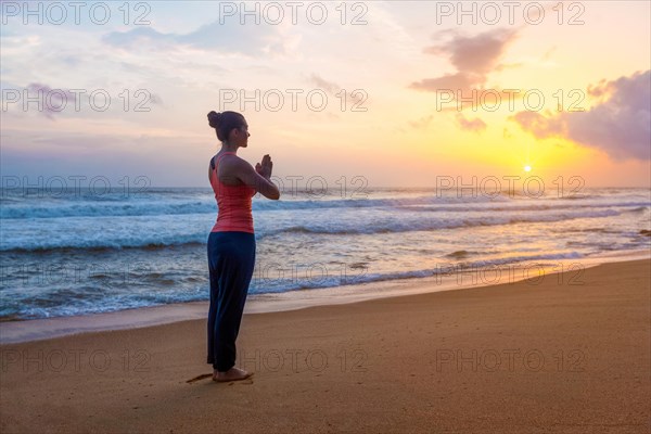 Woman doing Ashtanga Vinyasa Yoga asana Tadasana Samasthiti yoga posture on beach