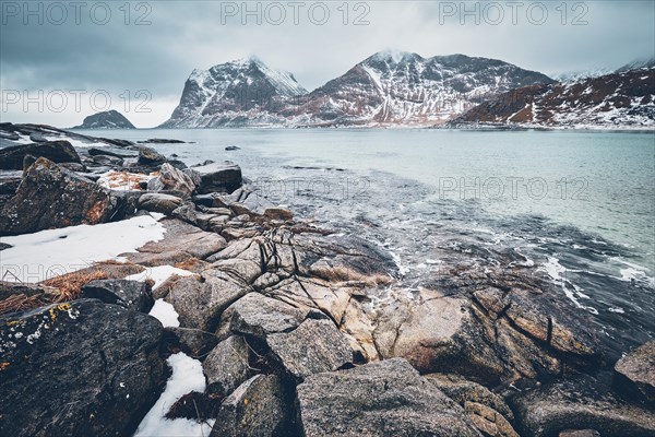 Rocky coast of fjord of Norwegian sea in winter with snow. Haukland beach