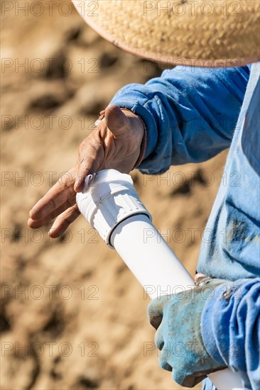 Plumber applying glue to PVC pipe at construction site