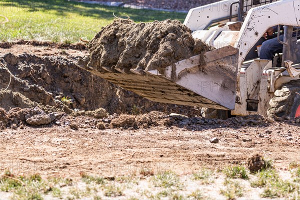 Small bulldozer digging in yard for pool installation