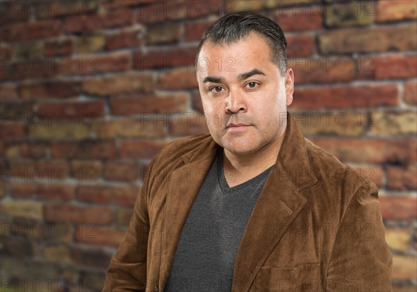 Handsome young hispanic male headshot portrait against brick wall