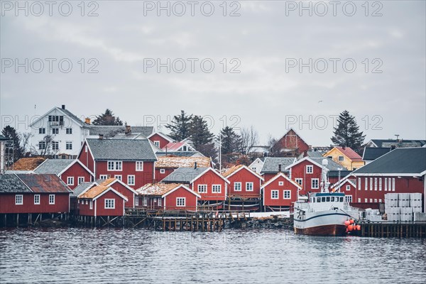 Reine fishing village on Lofoten islands with red rorbu houses in winter with snow with fishing boats. Norway