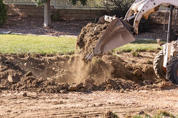 Small bulldozer digging in yard for pool installation