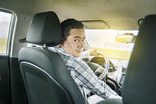 Happy young driver behind the wheel of a car. rear view of a smiling man behind the wheel