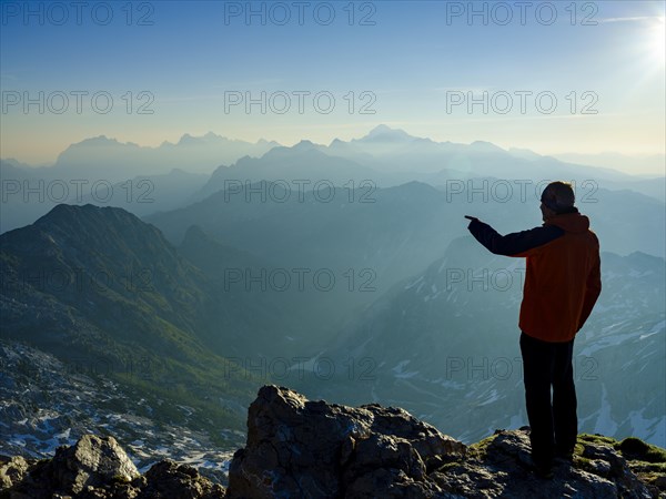 Climber at the summit of Krn 2. 244m pointing to his next target