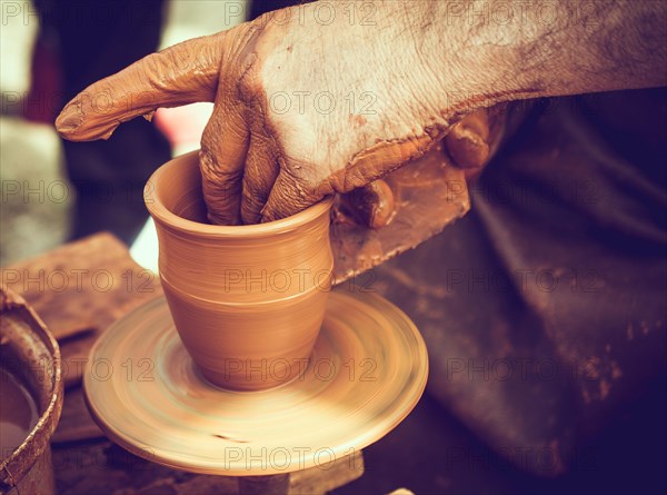 Potter`s hands shaping up the clay of the pot