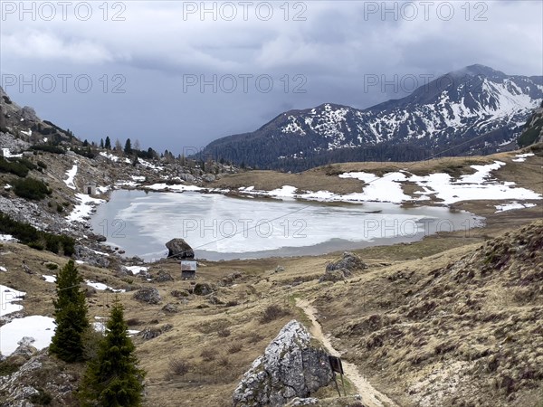 Mountain lake Lago di Valparola with thawing ice surface