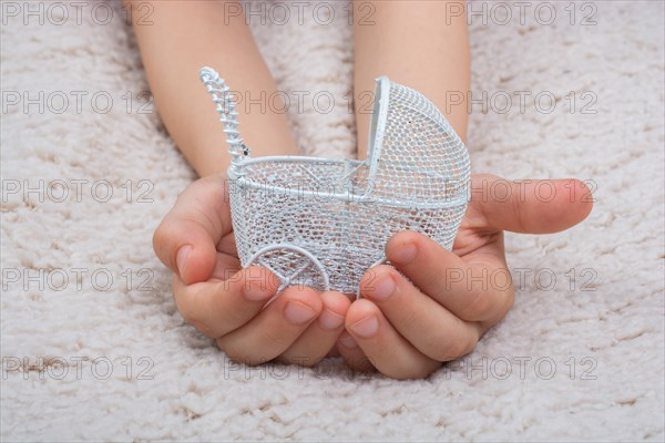 Little hands holding baby stroller on white background