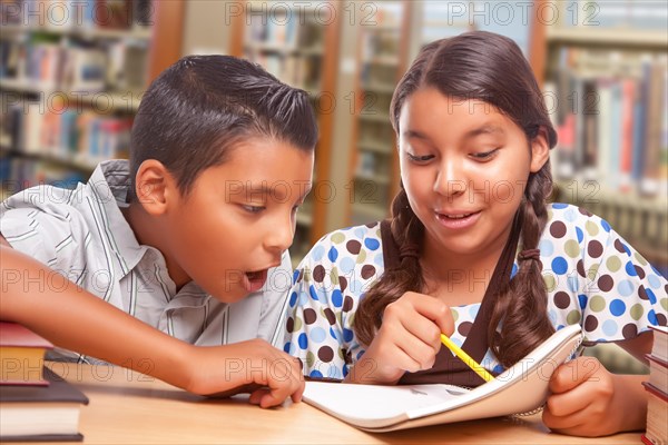 Hispanic boy and girl having fun studying together in the library