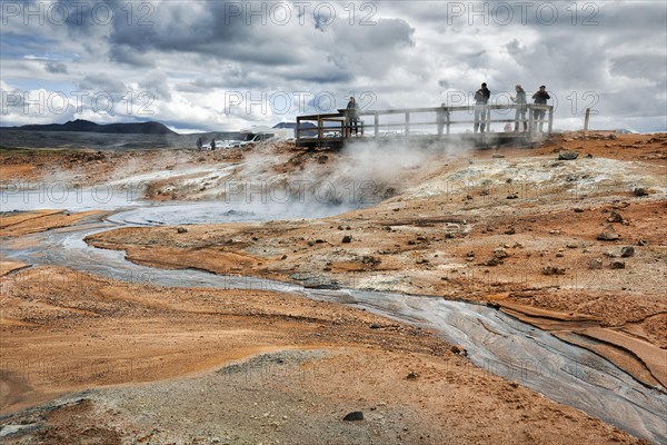 Tourists on viewing platform at steaming mud pot