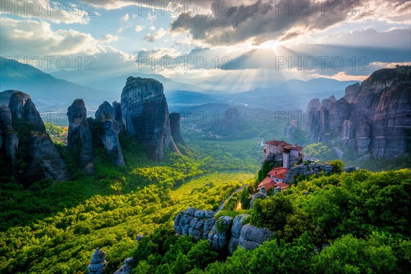 Sunset over monastery of Rousanou and Monastery of St. Nicholas Anapavsa in famous greek tourist destination Meteora in Greece on sunset with sun rays and lens flare and dramatic sky