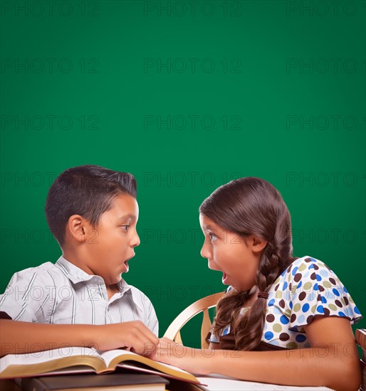 Blank chalk board behind hispanic boy and girl having fun studying together