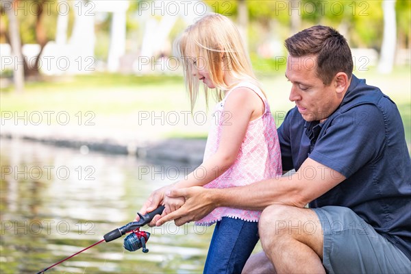 Young caucasian father and daughter having fun fishing at the lake