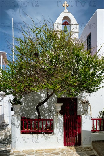 Picturesque scenic narrow Greek streets with traditional whitewashed houses with blue doors windows of Mykonos town and orthodox church in famous tourist attraction Mykonos island