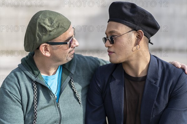 Gay Latino male couple sitting on a bench in a park