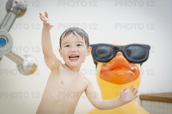 mixed-race boy having fun at the water park with large rubber duck in the background