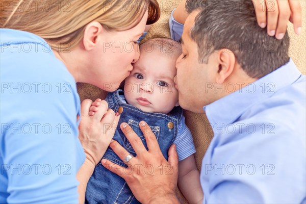 Young mixed-race couple laying with their infant on A blanket