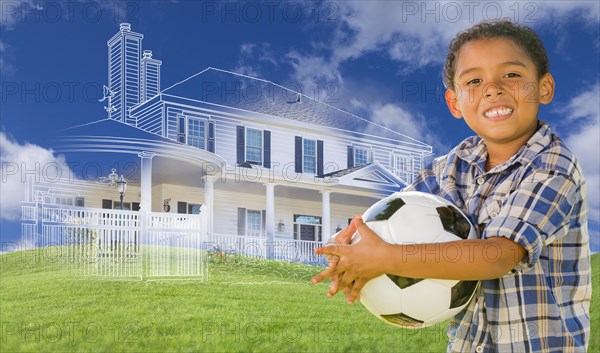 mixed-race young boy holding soccer ball with ghosted house drawing