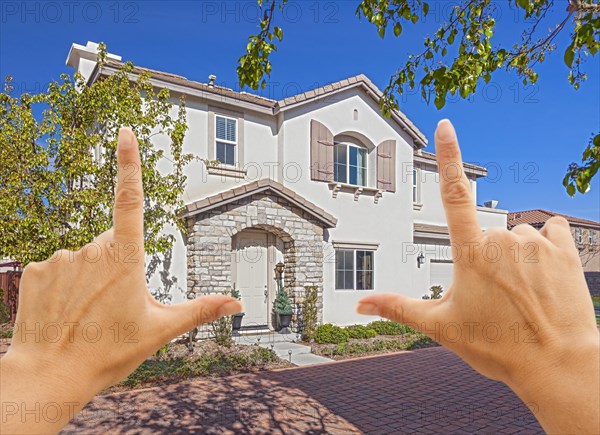 Female hands framing beautiful newly constructed house