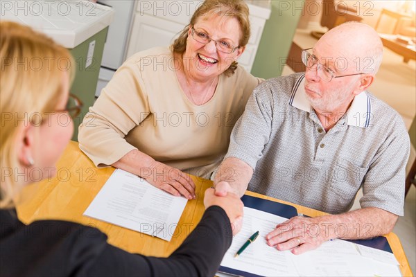 Senior adult couple going over documents in their home with agent at signing