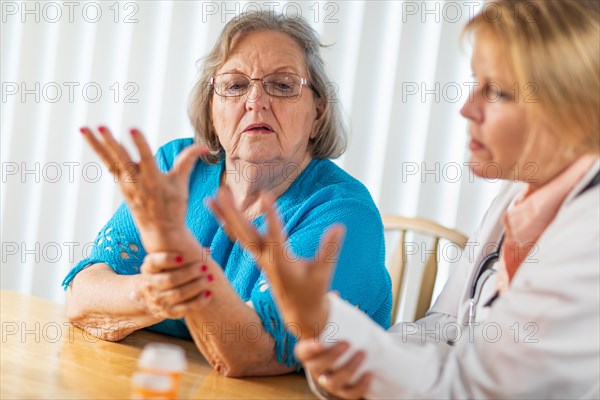 Female doctor talking with senior adult woman about hand therapy